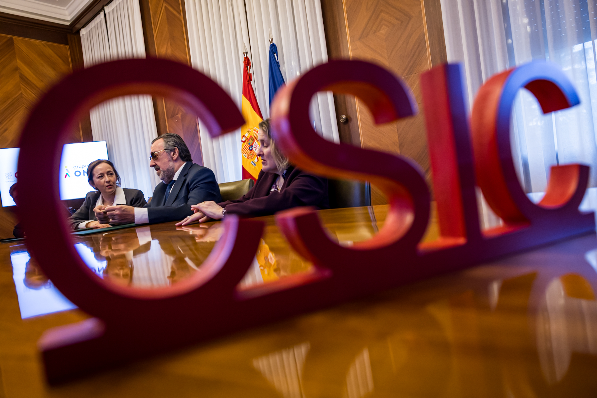 La presidenta del CSIC, Eloísa del Pino, junto a Miguel Carballeda y la vicepresidenta de Servicios Sociales del Consejo General de la ONCE, Imelda Fernández, en el acto de la firma del acuerdo. En primer plano las siglas del CSIC.