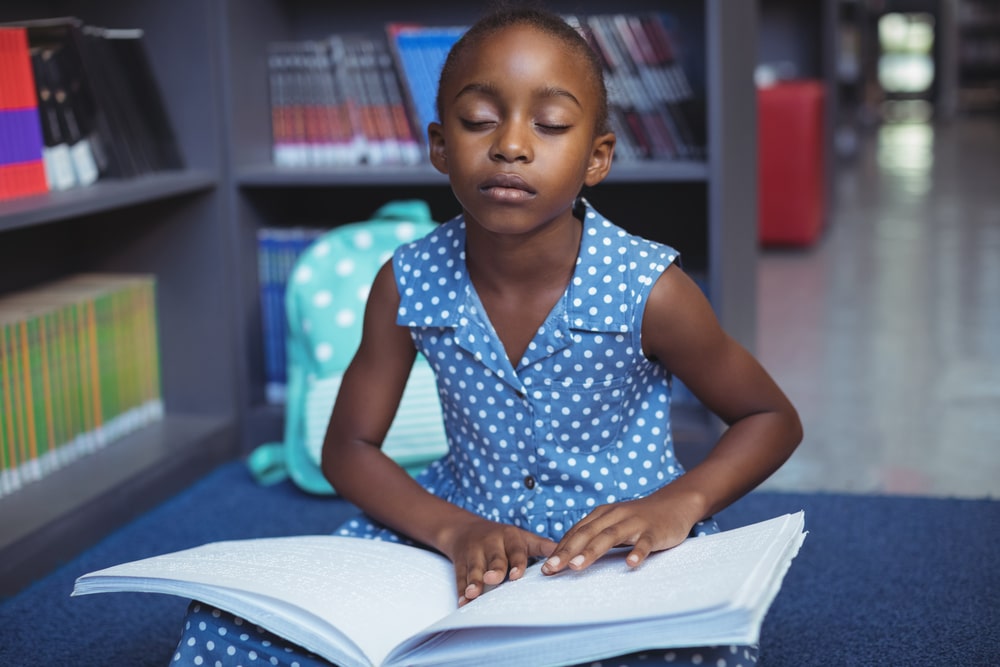Niña ciega leyendo un libro en braille