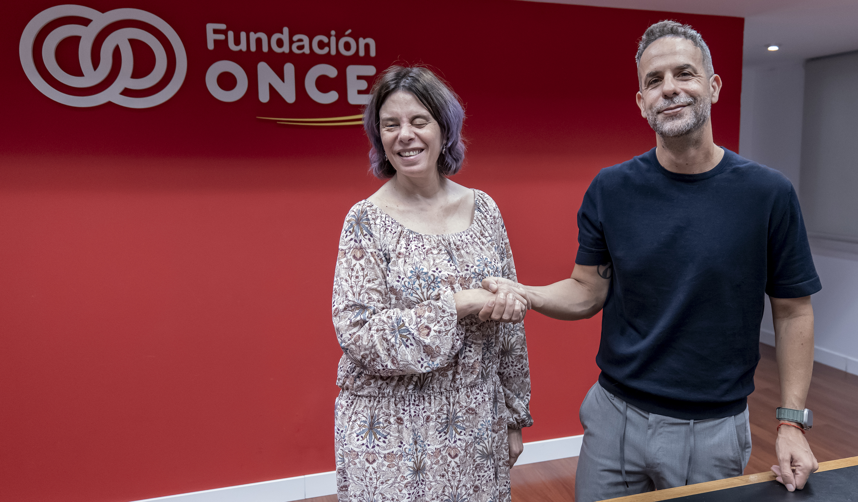 Virginia Carcedo y Alfredo Pérez se dan la mano durante la firma del acuerdo en la sede de Fundación ONCE