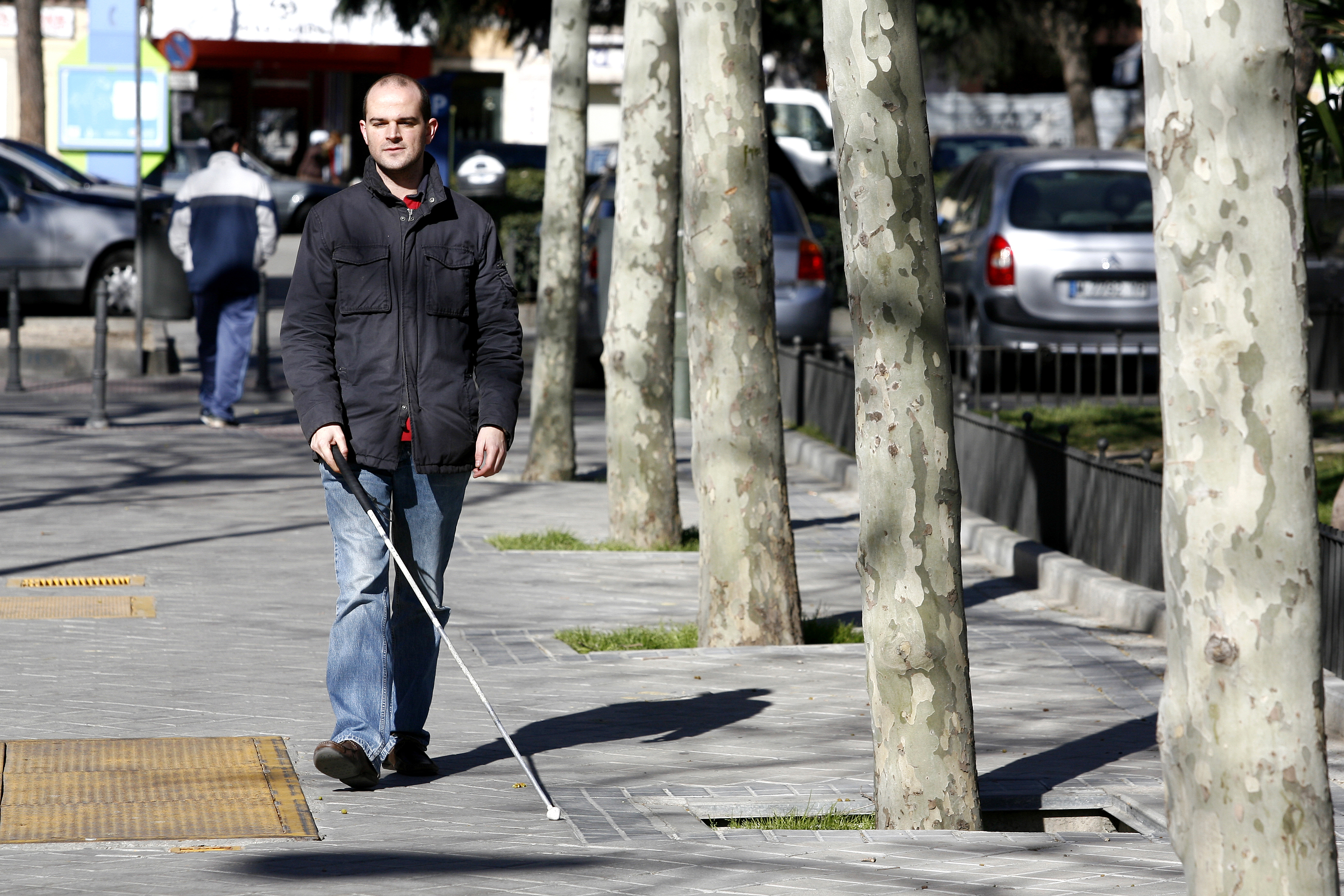 Una persona ciega deambula por la calle ayudado de un bastón blanco