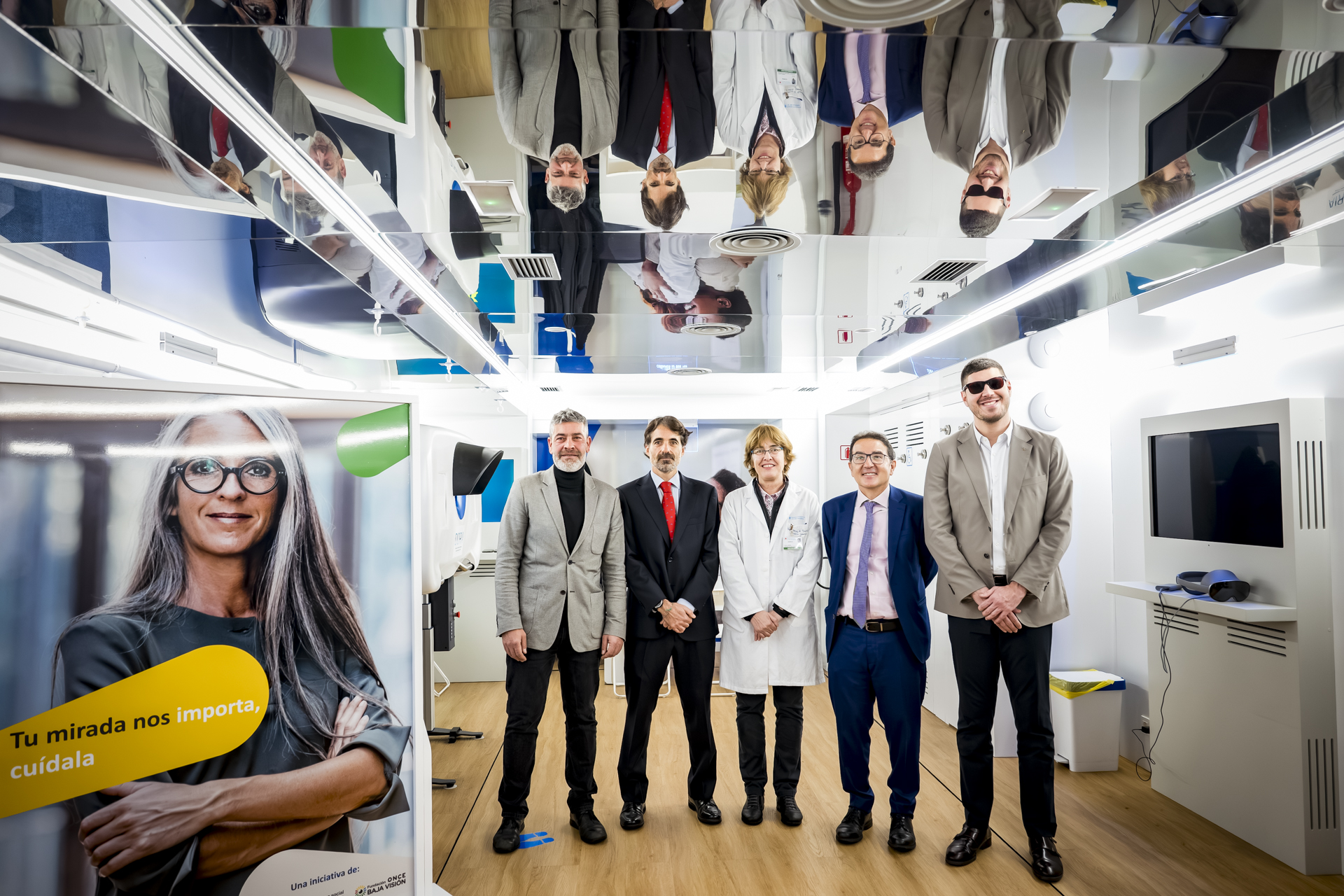 Foto de 5 personas al lado de un cartel dentro de la Unidad Móvil de salud visual